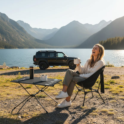 une femme boit son café de sa cafetière portable au bord d'un lac