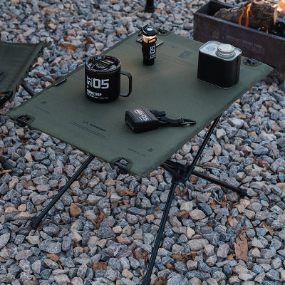 table camping verte sur un sol rocailleux